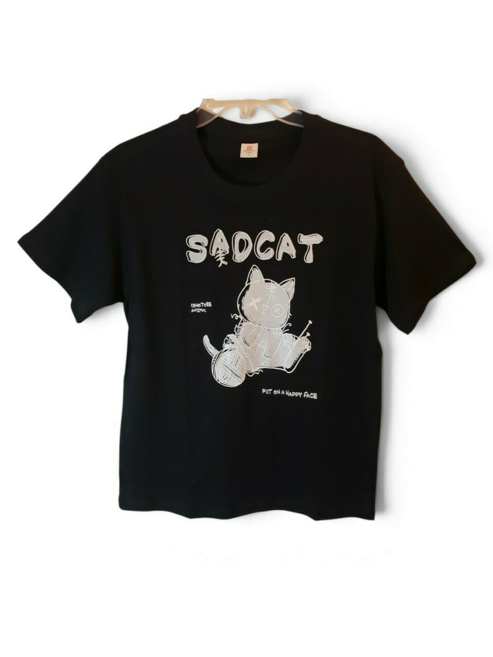 Gothic black short-sleeve graphic t-shirt with "SADCAT" text logo on the front.